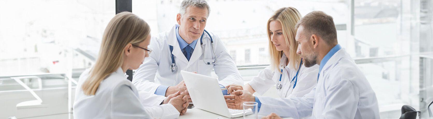 Four healthcare professionals in a meeting watching a laptop.