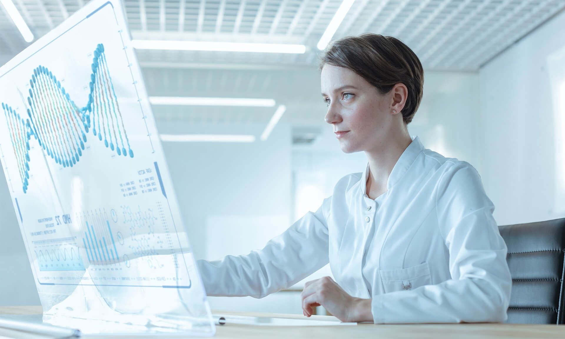 Young female doctor watching a hologram computer screen in a minimalistic office environment.