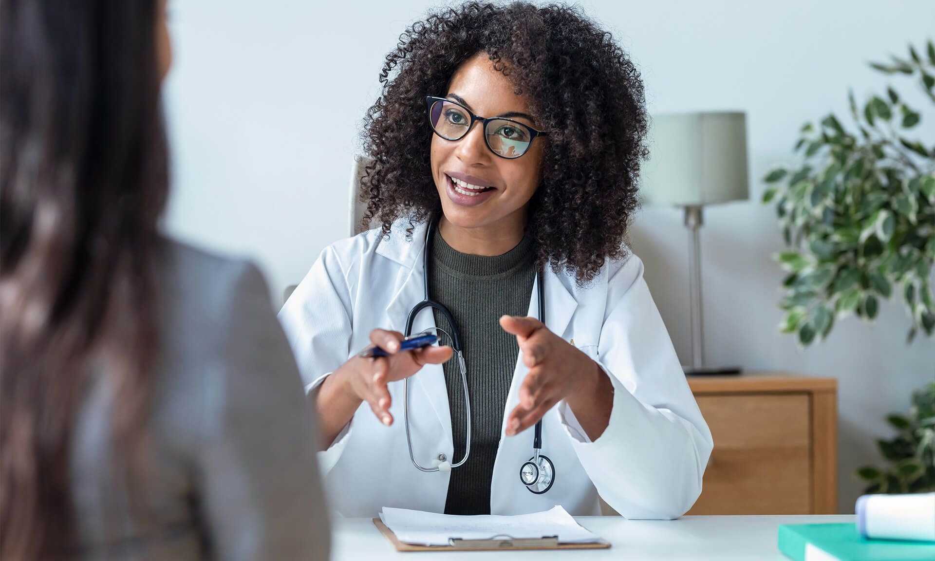 A female doctor meeting a female patient in an office environment.