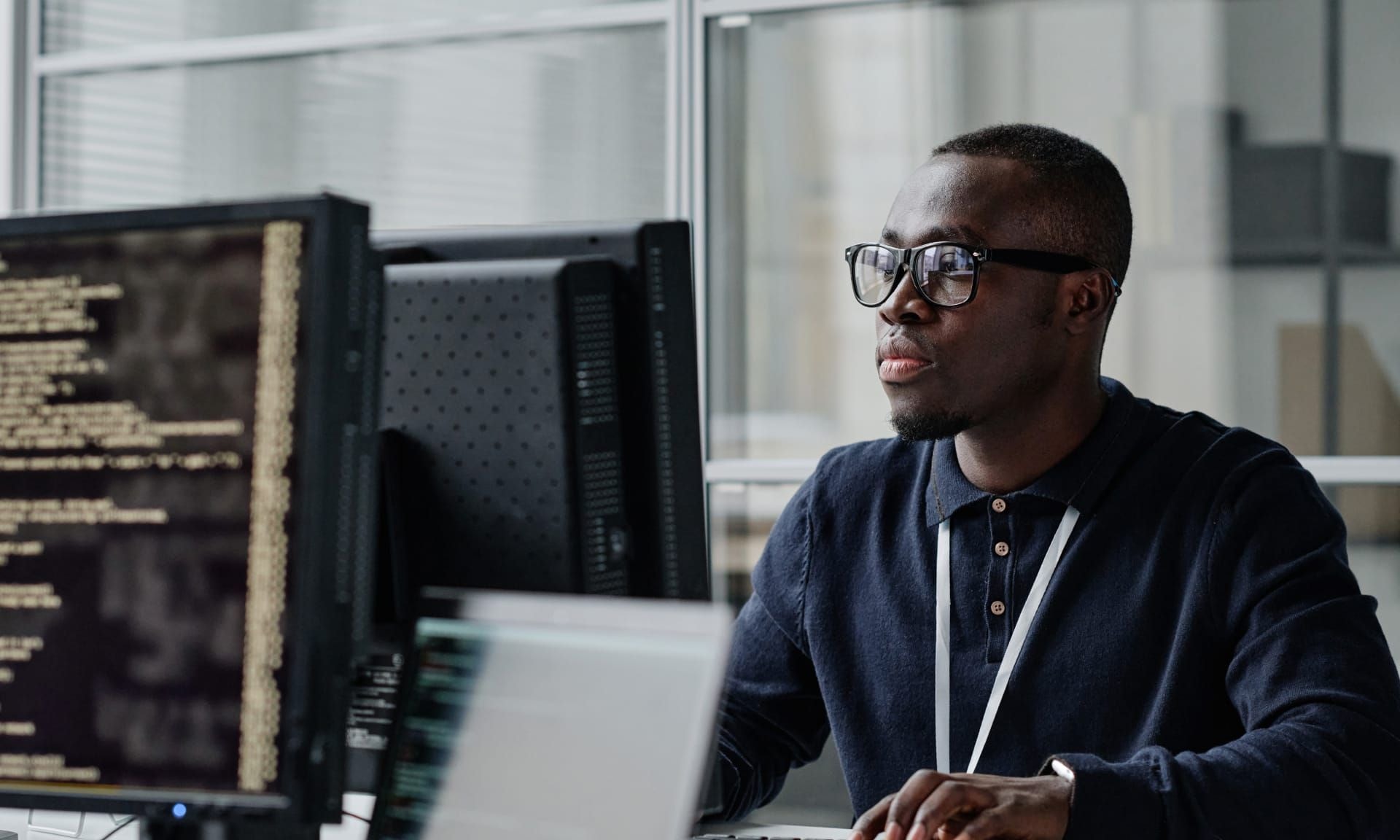 A male healthcare professional working by a computer wearing a blue shirt.