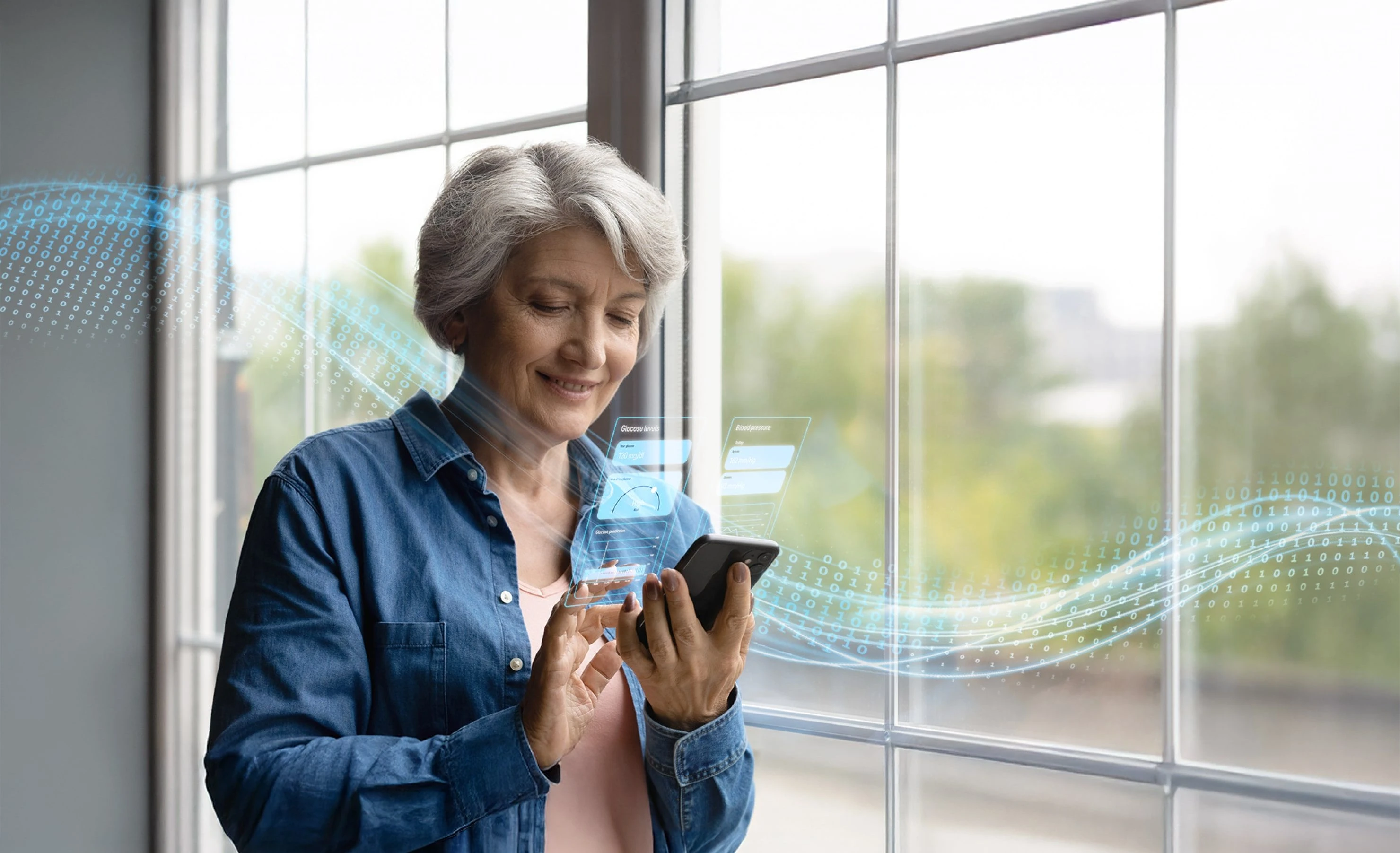 A woman views health data on her smartphone while standing in front of a window.