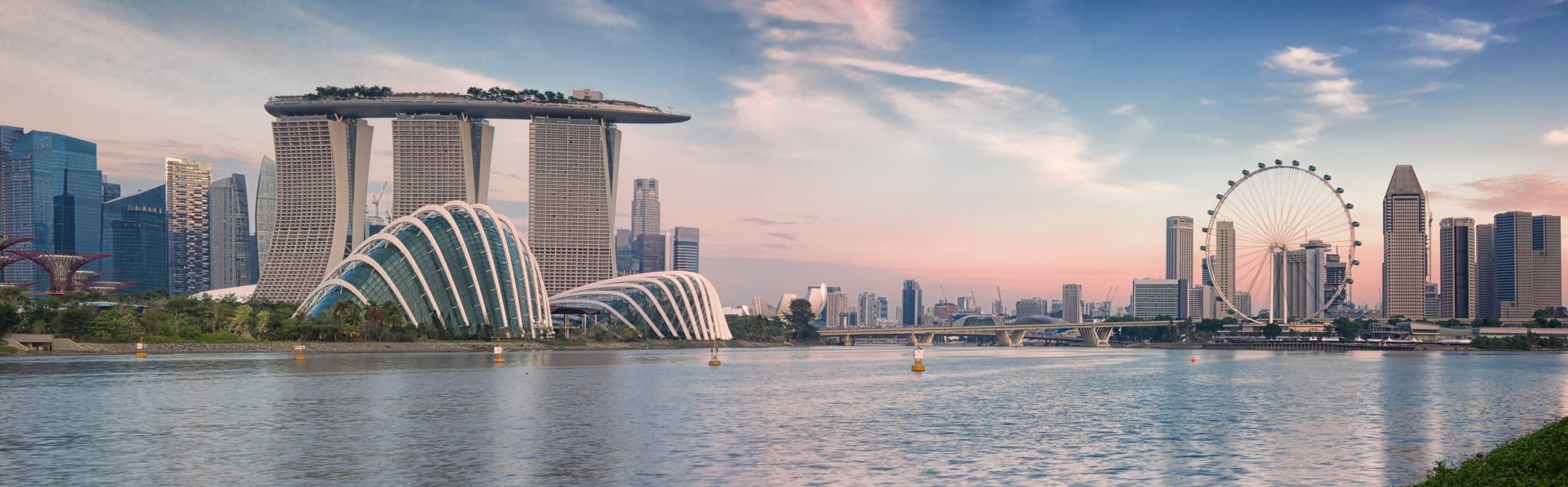 A wide shot of the Singapore skyline featuring Marina Bay Sands and the Singapore Flyer at sunset.