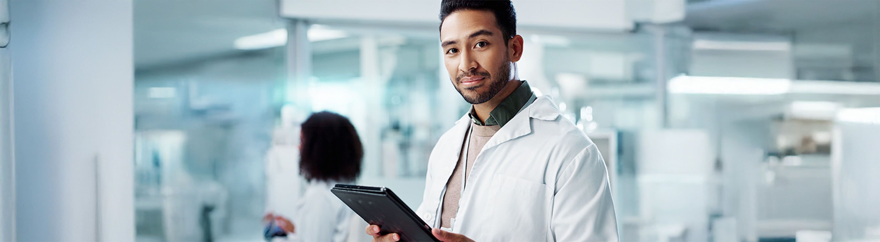 Male lab professional standing and holding a tablet device.