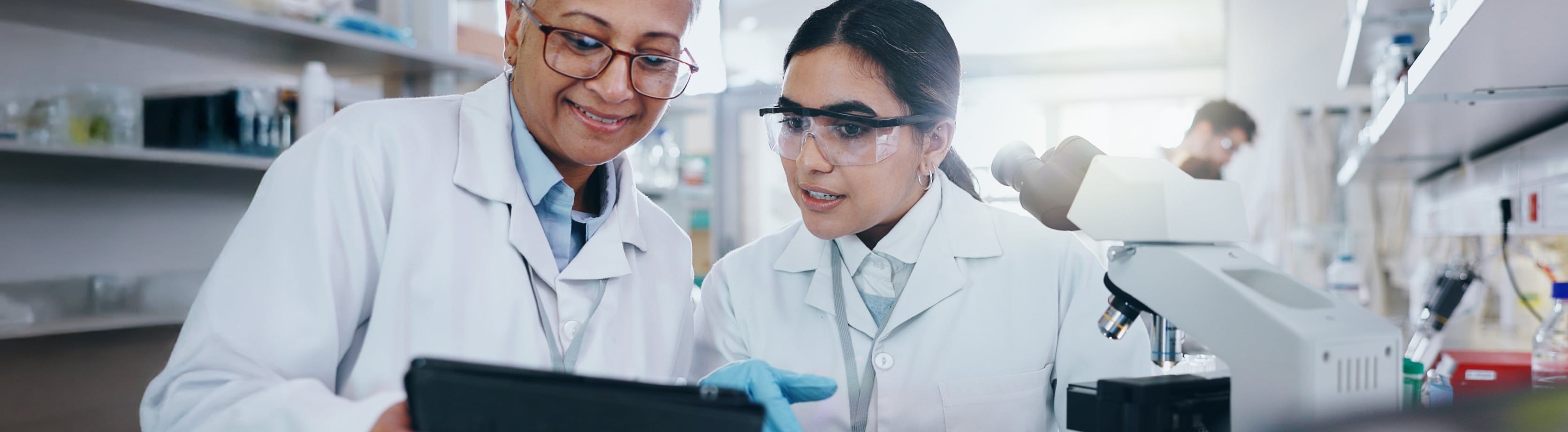 Two female lab technicians looking at a tablet.