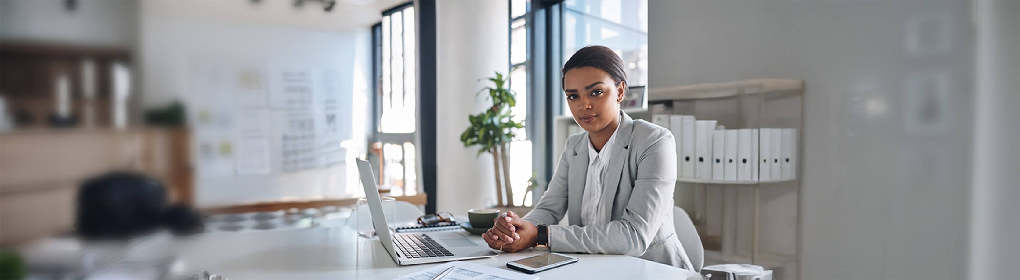 A confident business professional sitting at her desk with a laptop, radiating focus and determination in a modern office.