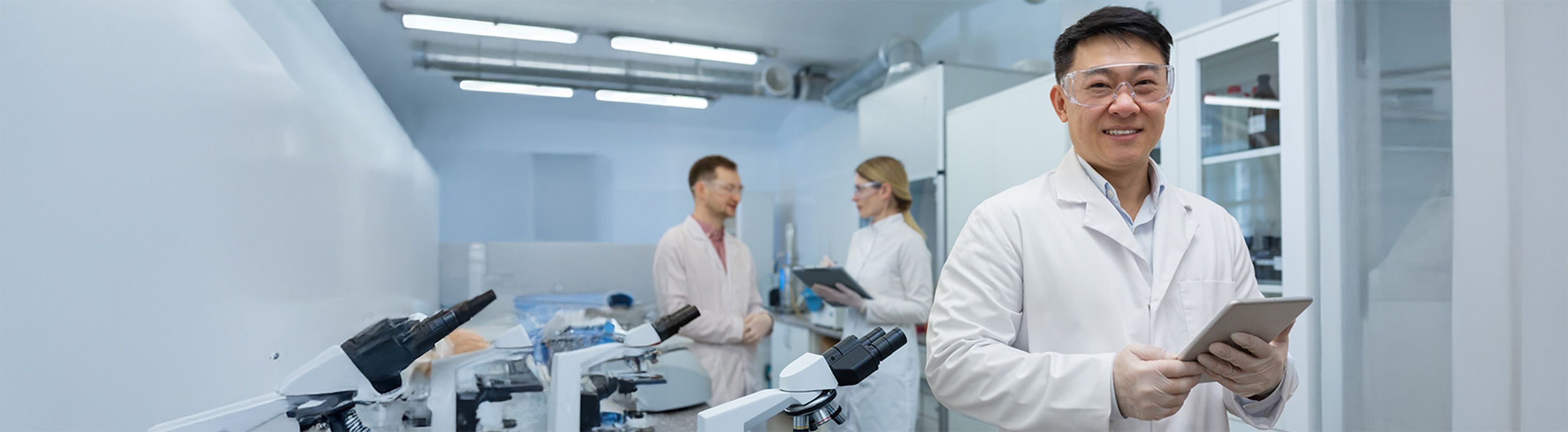 Three lab technicians wearing protective goggles in a lab environment.