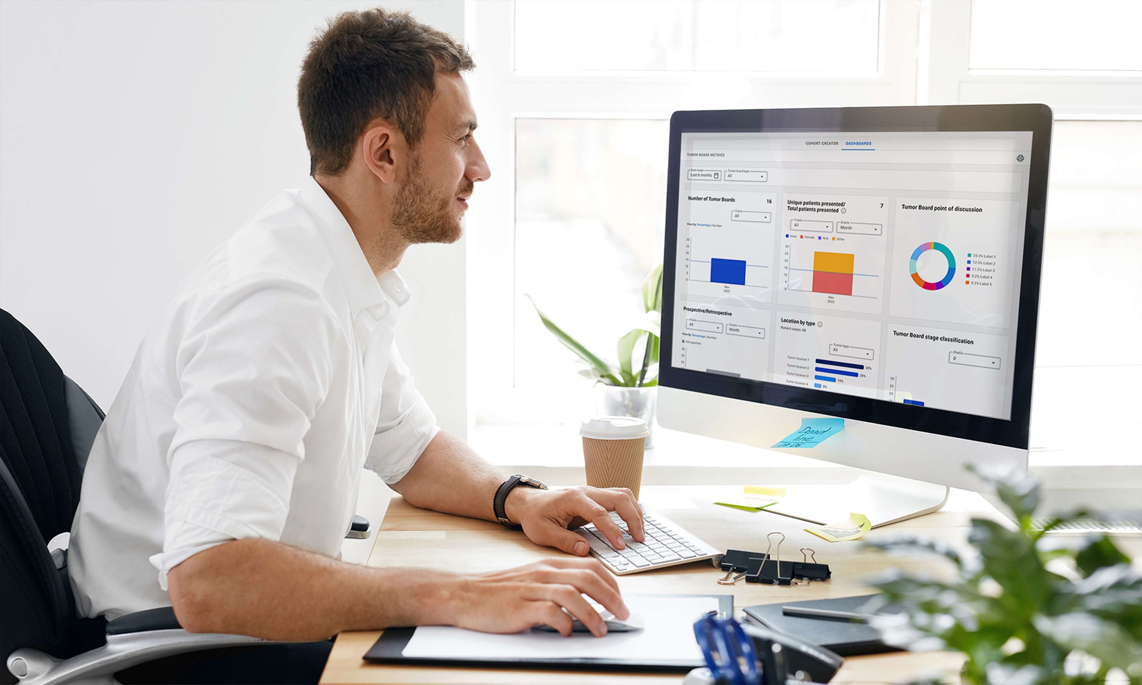A male healthcare professional working at his desk and watching a computer screen.