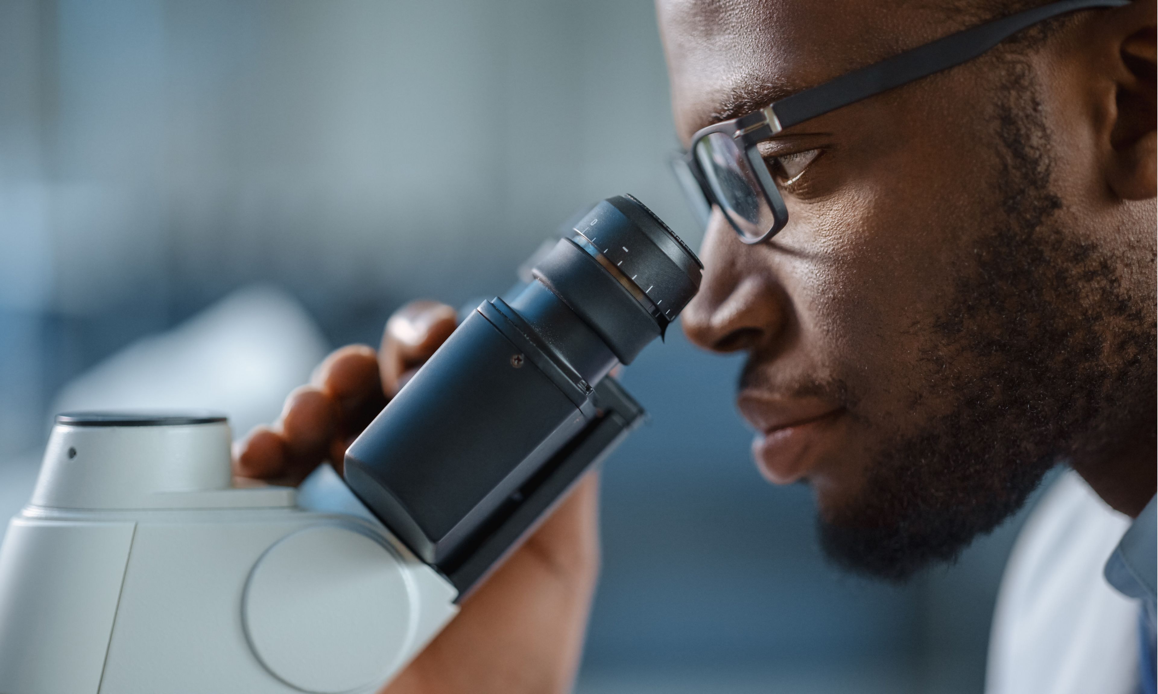 A scientist closely examines a sample using a laboratory microscope in a research setting.