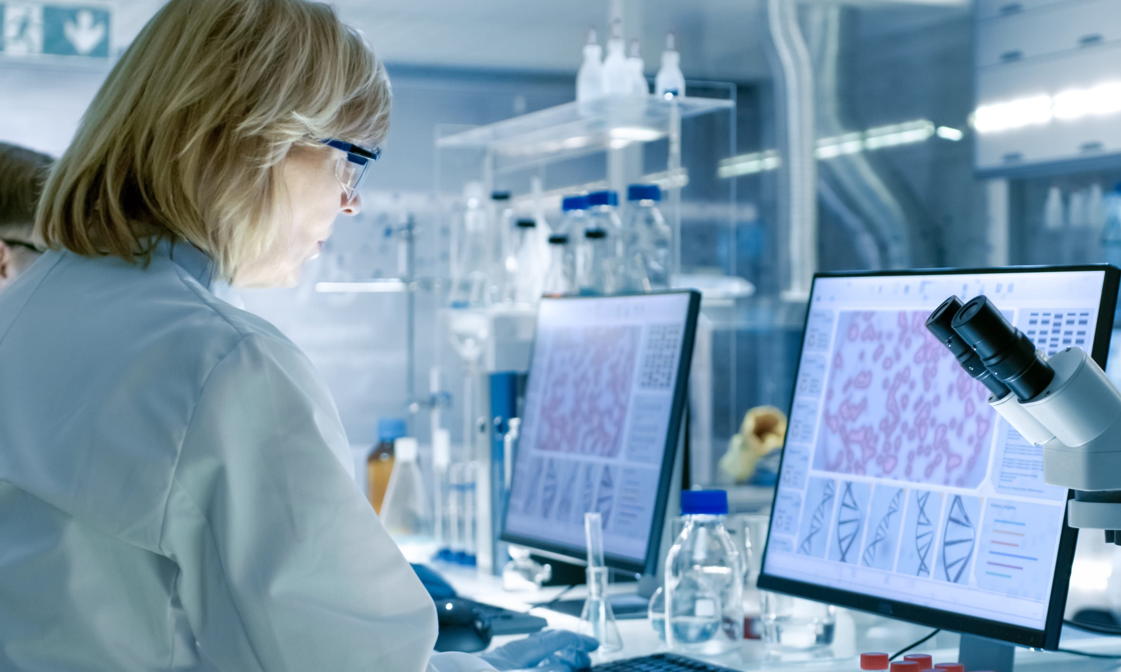 Female lab professional working by a computer screen in a laboratory.