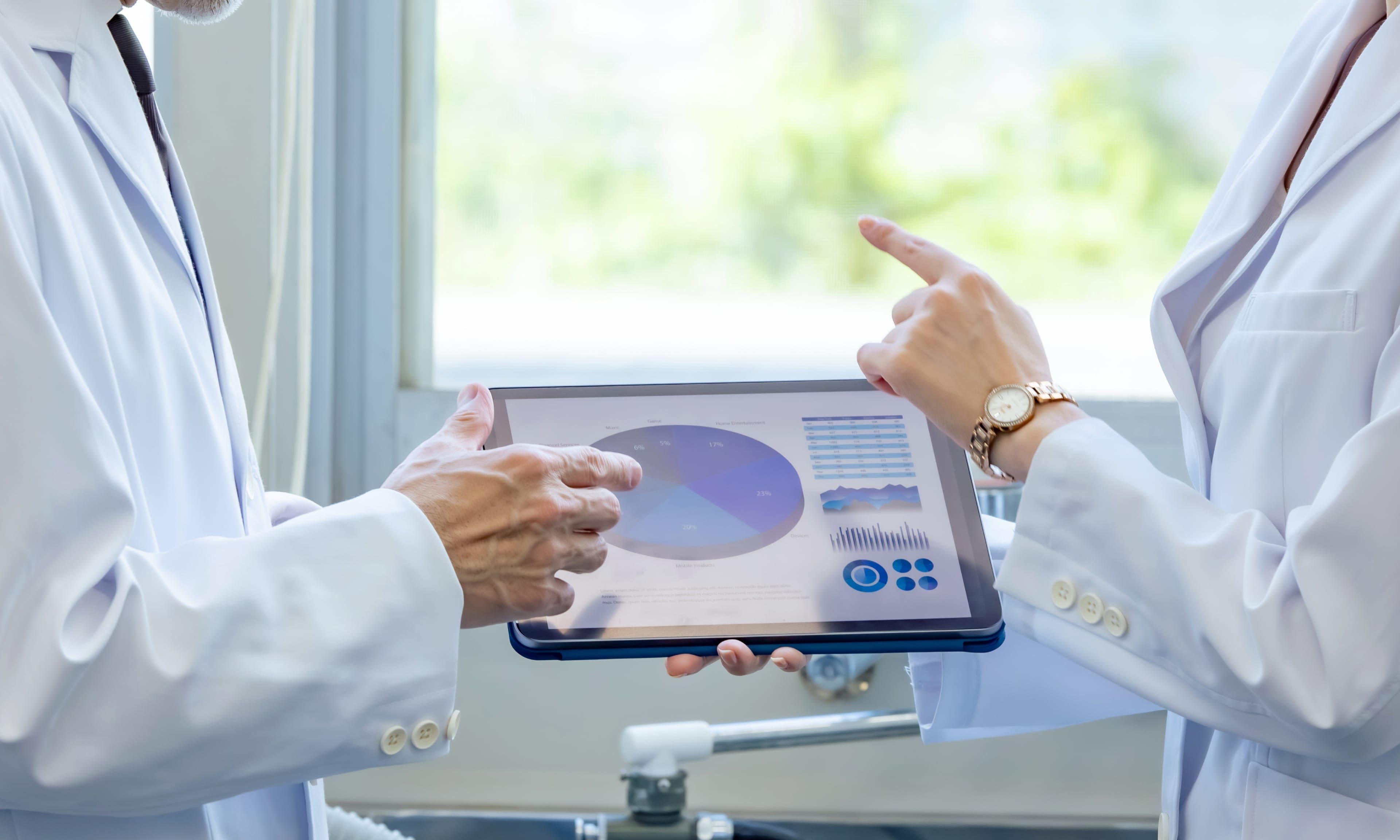 Two healthcare professionals standing by a tablet device displaying a dashboard.
