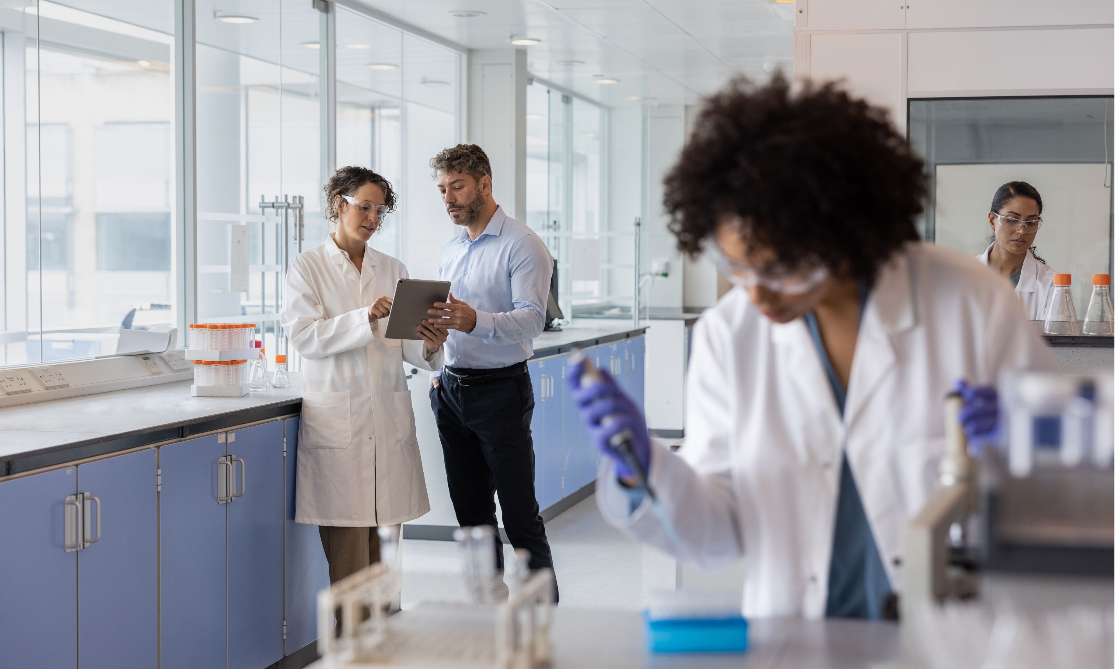 Scientists collaborate in a laboratory, discussing research findings and conducting experiments at workstations.