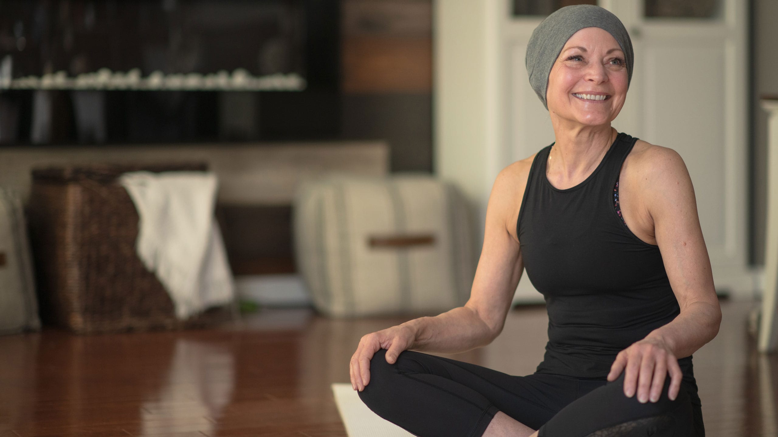 A cancer patient in yoga wear looking happy